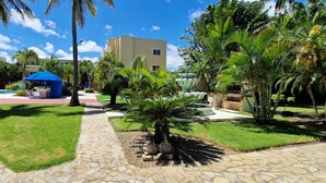 Cortile di un resort con piscina, palme e una struttura dal tetto blu.