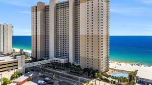 Ein Hochhaus-Hotel mit mehreren Etagen, einem Pool und Blick auf den Strand.