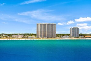 Un hôtel situé sur la côte, composé de plusieurs immeubles de grande hauteur, avec une plage et une eau cristalline.