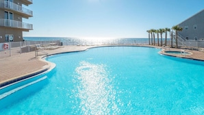 Ein klarer, blauer Pool mit gewölbter Kante, umgeben von einer Ziegelterrasse und einem weißen Geländer.