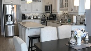 A modern kitchen with white cabinetry, stainless steel appliances, and a central island.
