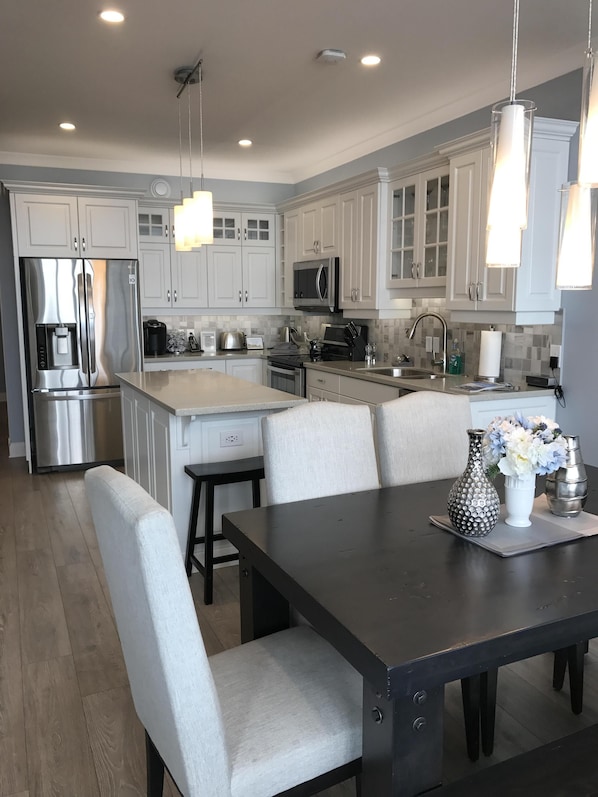 Una cocina moderna con armarios blancos, electrodomésticos de acero inoxidable y una isla central.