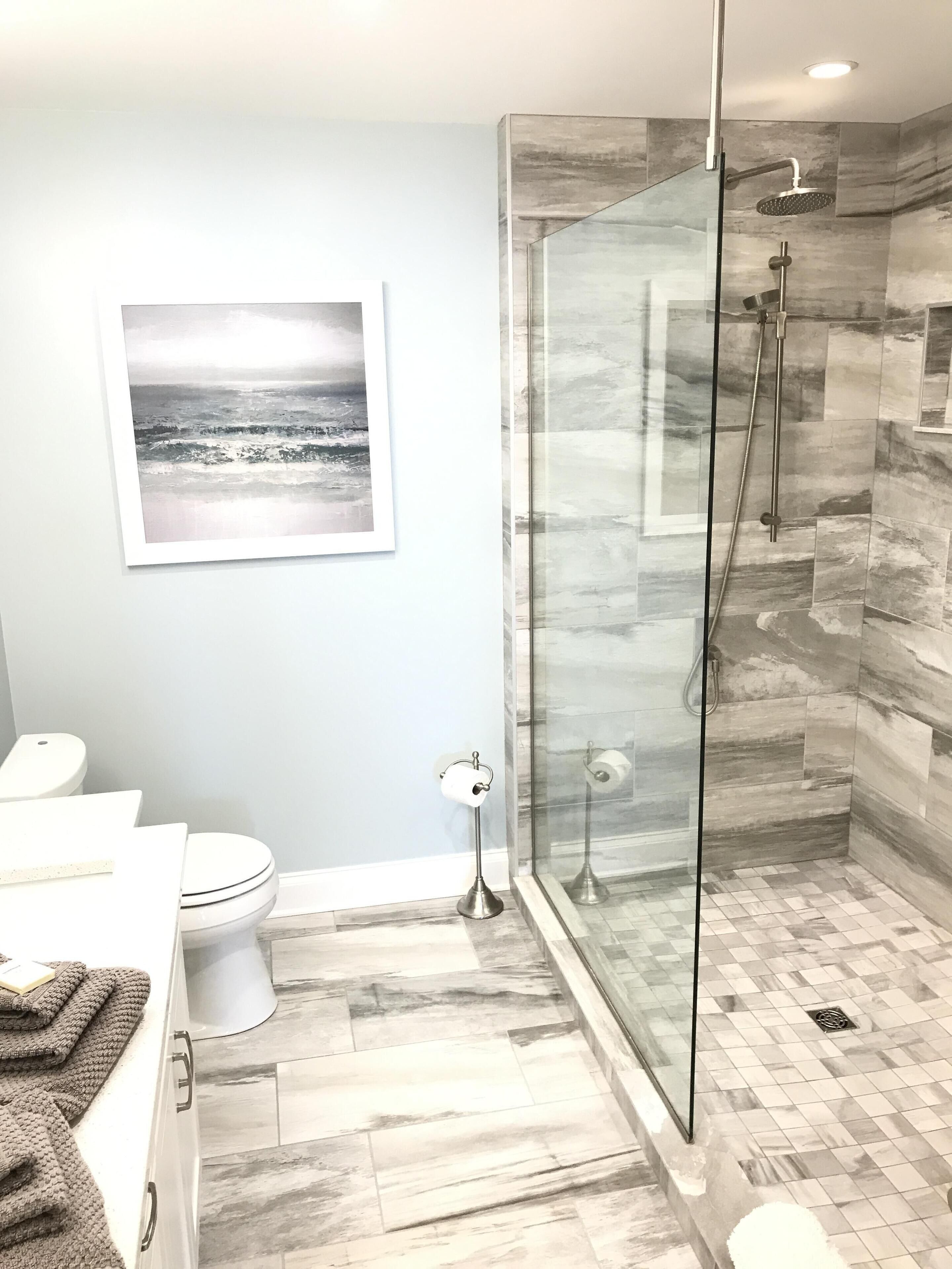A modern bathroom with a glass-enclosed shower, a toilet, and a sink.