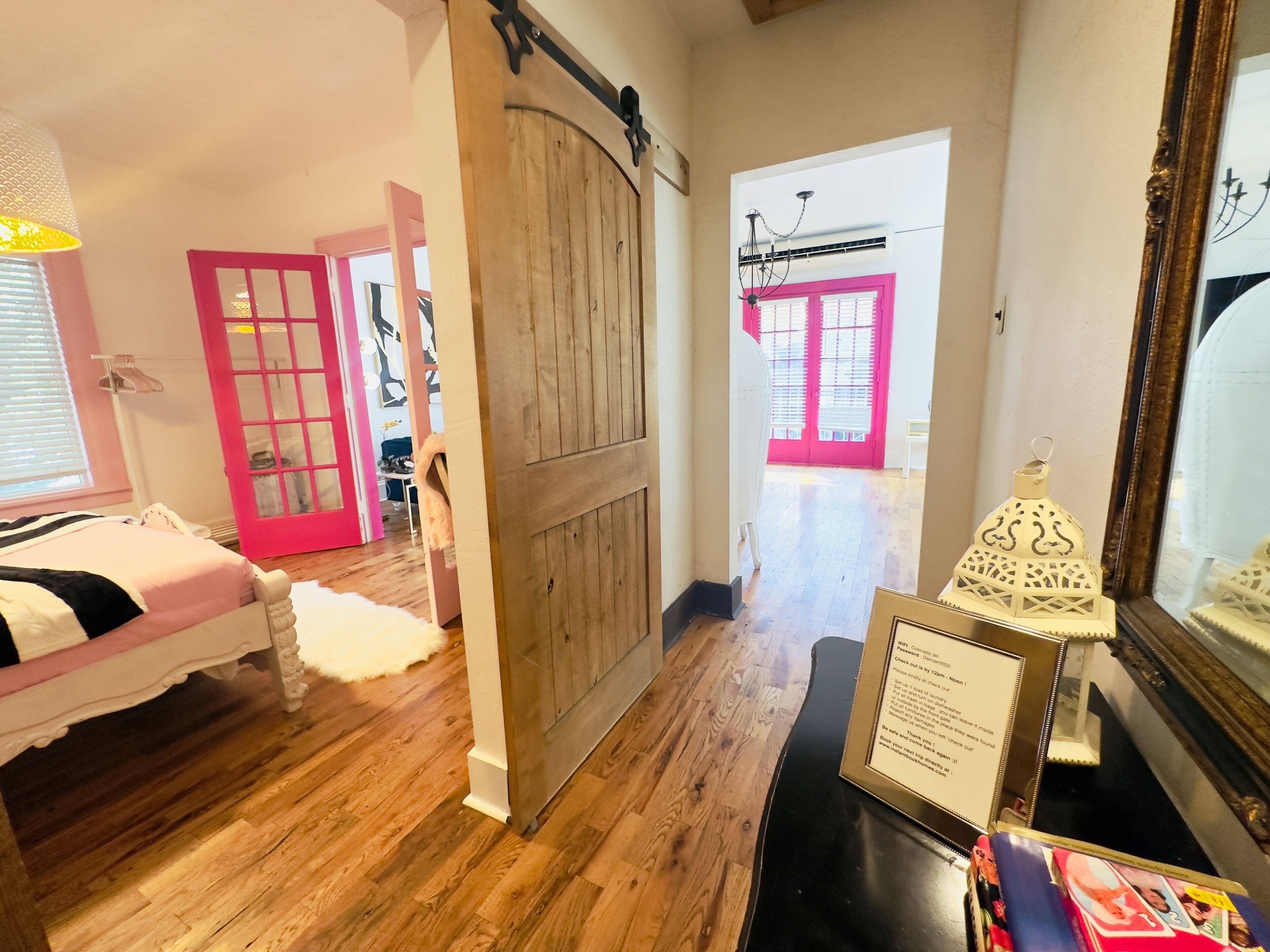 A room with a bed, a wooden door, a hallway, and a dining area with a table and chairs.