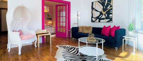 A modern living room with a zebra rug, a white chair, a blue sofa, and a chandelier.