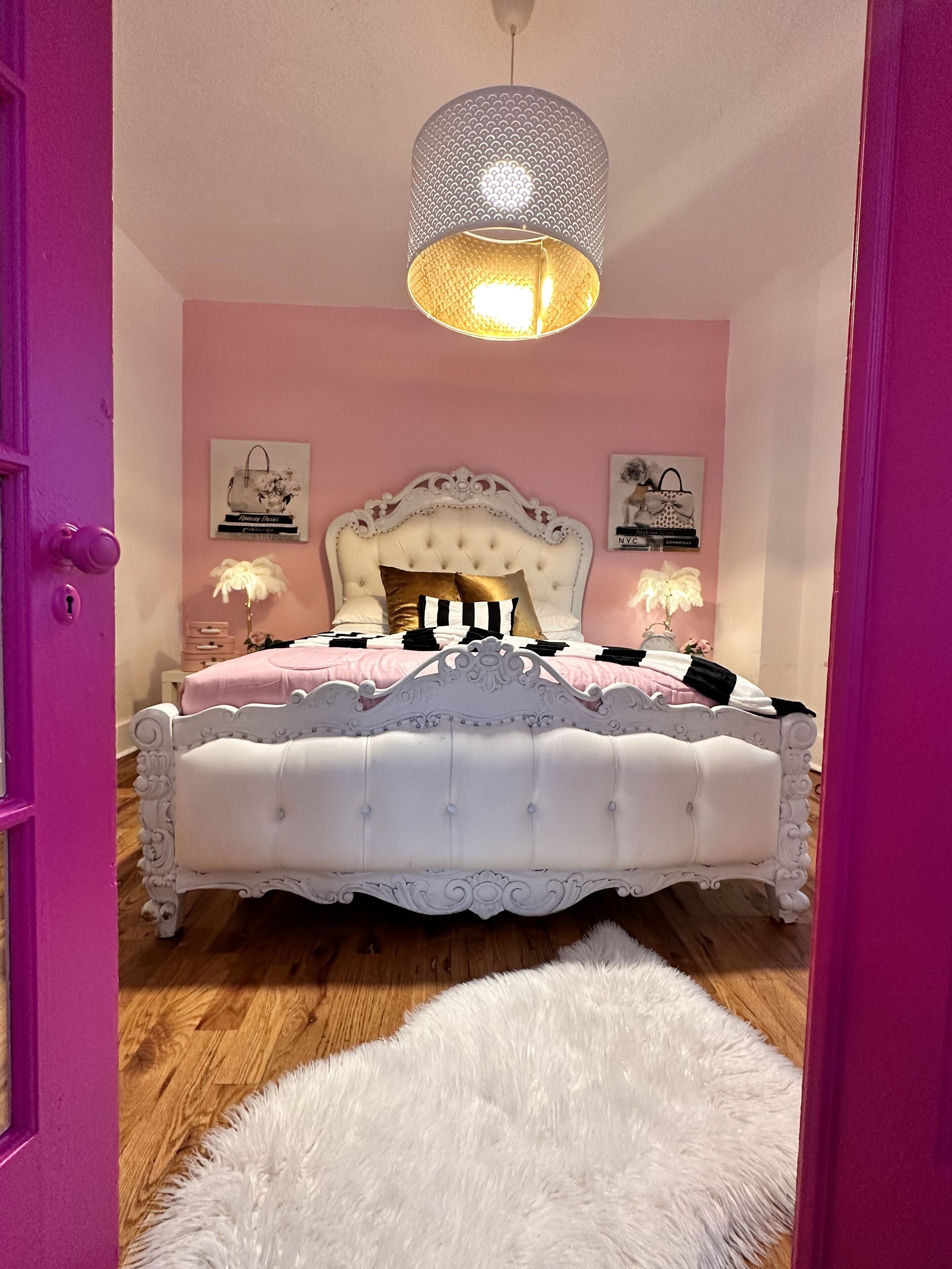 A bedroom with a white tufted bed, pink walls, and a fluffy white rug.