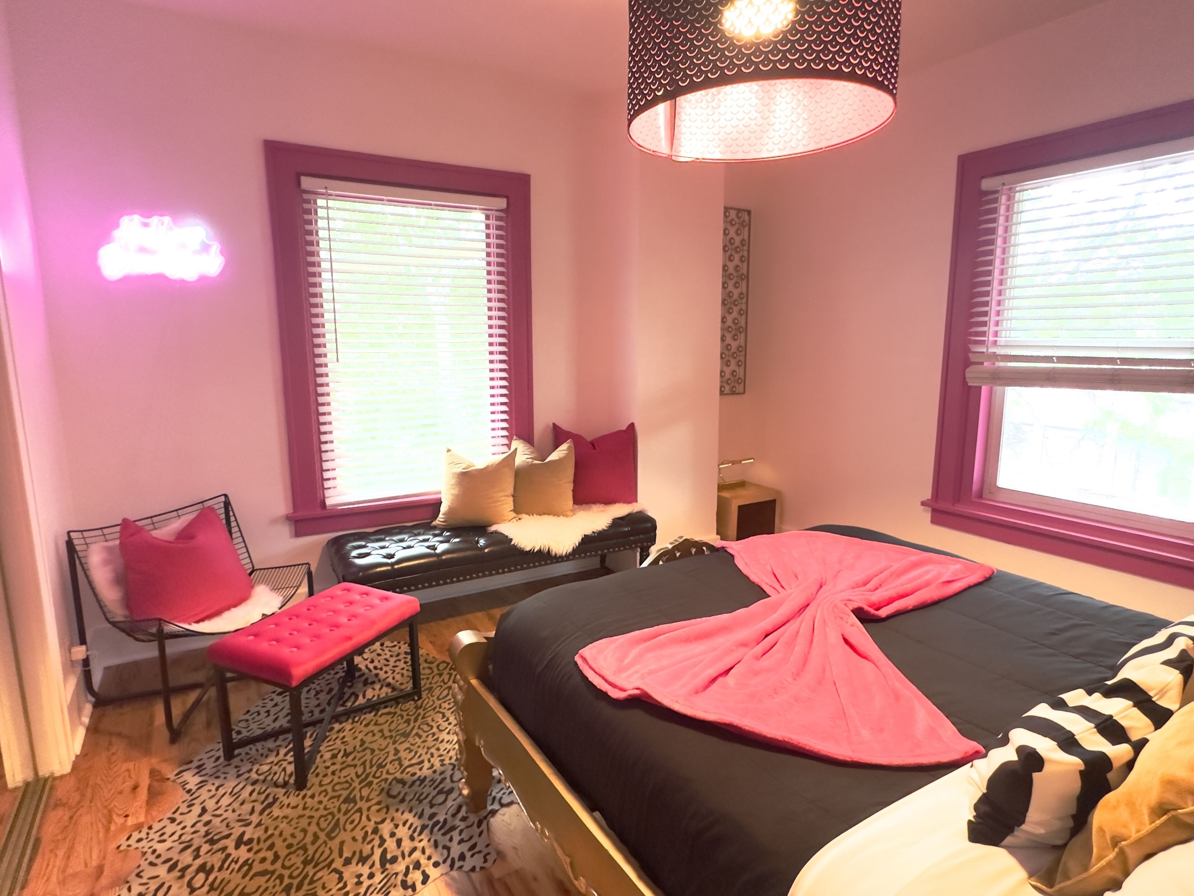 A bedroom with a bed, a chair, a small table, and a window with blinds.