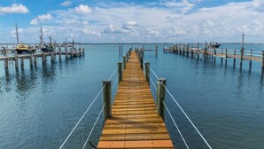Un muelle de madera se adentra en aguas tranquilas, con barcos amarrados en los extremos.