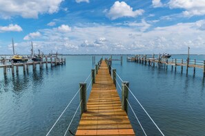 Un muelle de madera se adentra en aguas tranquilas, con barcos amarrados en los extremos.