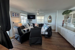 A living room with a sofa set, a television, and a ceiling fan.