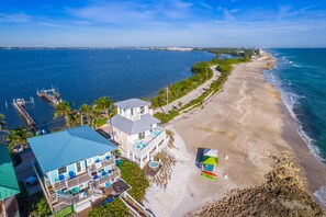 A beachfront property with a large house, a dock, and a sandy beach.