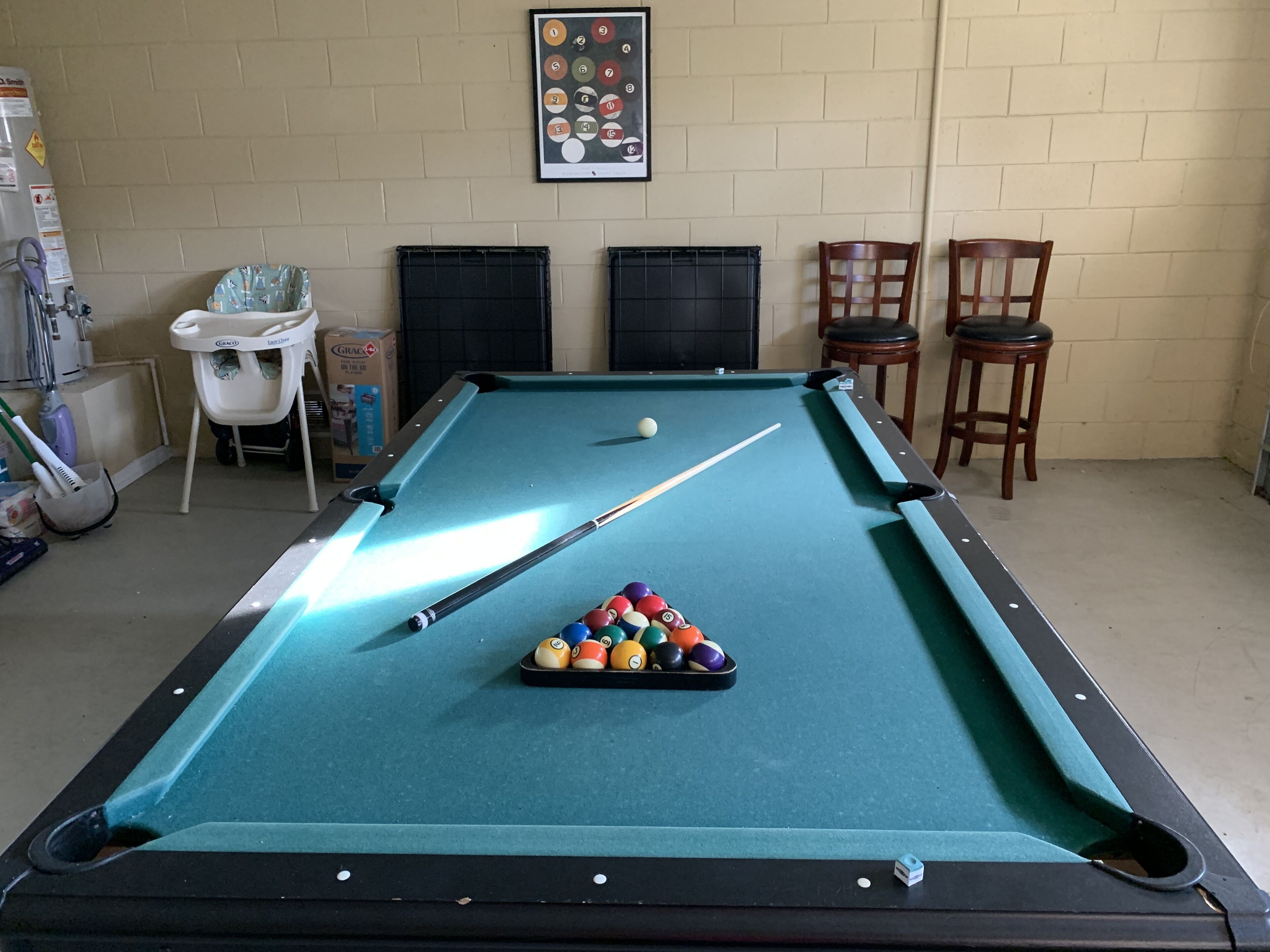 A pool table with balls, chairs, and a framed picture on the wall.