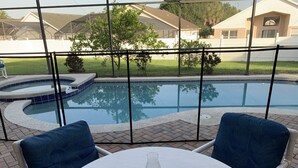 A patio with a table and chairs, a glass-top table, a decorative candle holder, and a view of a swimming pool through a screened area. - Pet-Friendly Fenced Home w/Pool & Spa Heat - 3 Miles from Disney (Kissimmee)