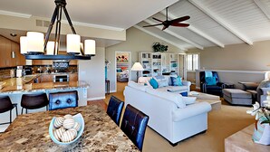 A spacious living area with a large white sofa, a dining table with a bowl of cookies, and a ceiling fan. - Enjoyable and Luxurious Carlsbad Village Beach House 1/2 Block to Beach (Carlsbad)