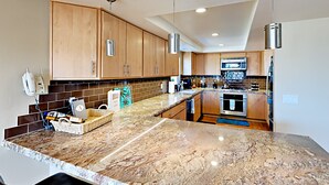 A modern kitchen with granite countertops, wooden cabinets, and stainless steel appliances. - Enjoyable and Luxurious Carlsbad Village Beach House 1/2 Block to Beach (Carlsbad)