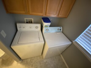 Compact laundry room with two front-loading washing machines and wooden cabinets.