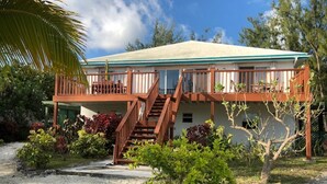 A two-story house with a balcony, a staircase, and a sandy driveway. - LARGE 4 Bed/4Bath BEACHFRONT APARTMENT SLEEPS 8 and directly  on HOOPERS BAY (Georgetown)