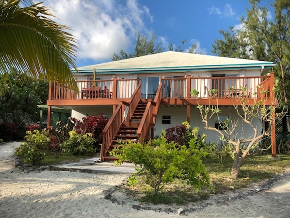 A two-story house with a balcony, a staircase, and a sandy driveway. - LARGE 4 Bed/4Bath BEACHFRONT APARTMENT SLEEPS 8 and directly  on HOOPERS BAY (Georgetown)
