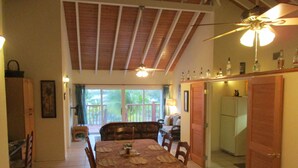 A dining area with a table set for four, a ceiling fan, and a view of the outdoors through a sliding door. - LARGE 4 Bed/4Bath BEACHFRONT APARTMENT SLEEPS 8 and directly  on HOOPERS BAY (Georgetown)