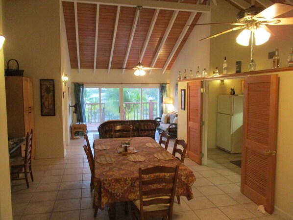 A dining area with a table set for four, a ceiling fan, and a view of the outdoors through a sliding door. - LARGE 4 Bed/4Bath BEACHFRONT APARTMENT SLEEPS 8 and directly  on HOOPERS BAY (Georgetown)