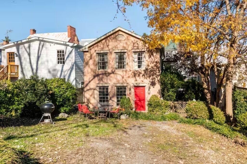 A two-story house with a red door and a chimney.
