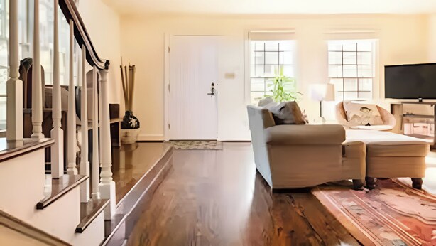 A spacious living room with a staircase, a sofa, a television, and a large window. - BEST LOCATION: Historic Shepherdstown Getaway (Shepherdstown)