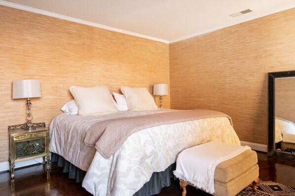Une chambre avec un grand lit, deux tables de chevet avec des lampes, un miroir et un mur en bois.