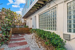 A residential building with a wooden deck, a small garden with gravel pathways, and a large window with a grid pattern. - 3 Florida side-by-side Beach Houses; Sleeps 50+. Pools, Hot Tubs, Docks ON Beach (Stuart)