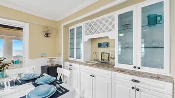 A kitchen with white cabinets, a granite countertop, and a dining area with a table set for four.