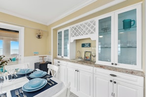 A kitchen with white cabinets, a granite countertop, and a dining area with a table set for four. - 3 Florida side-by-side Beach Houses; Sleeps 50+. Pools, Hot Tubs, Docks ON Beach (Stuart)