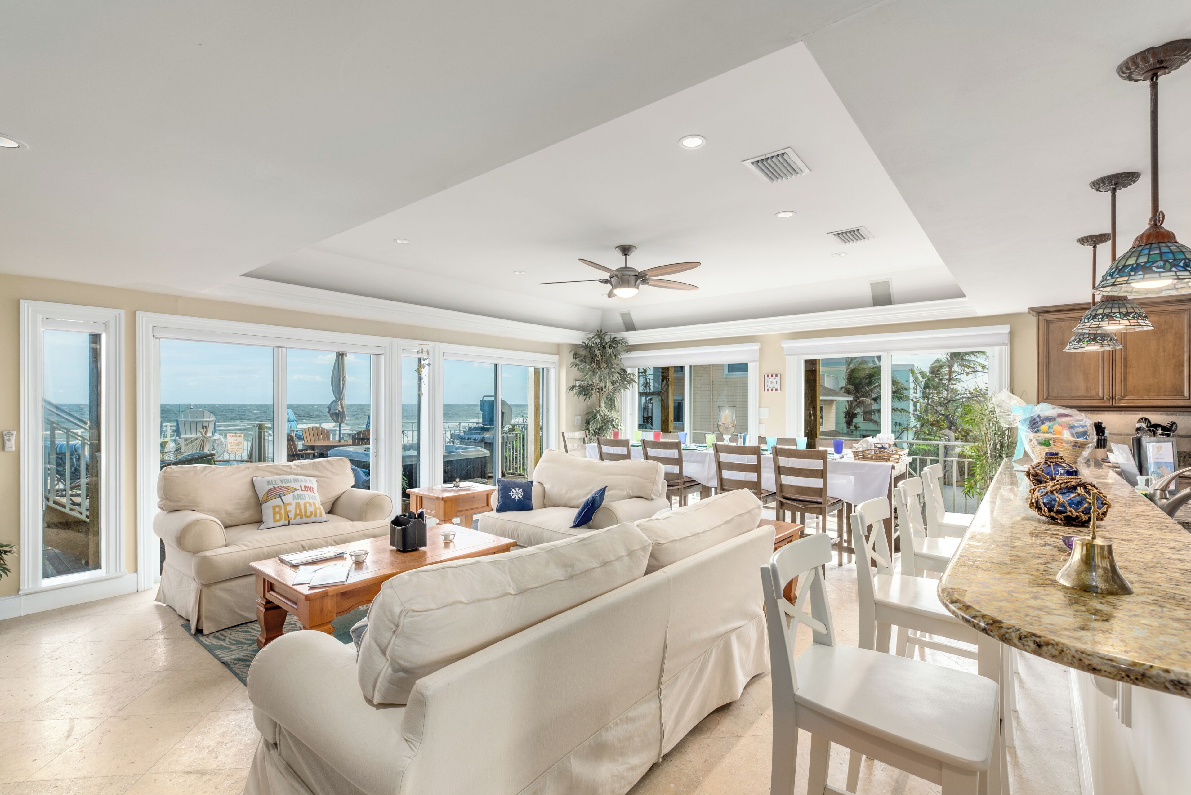 A spacious living room with a large sofa, a dining area, and a kitchen with a bar.