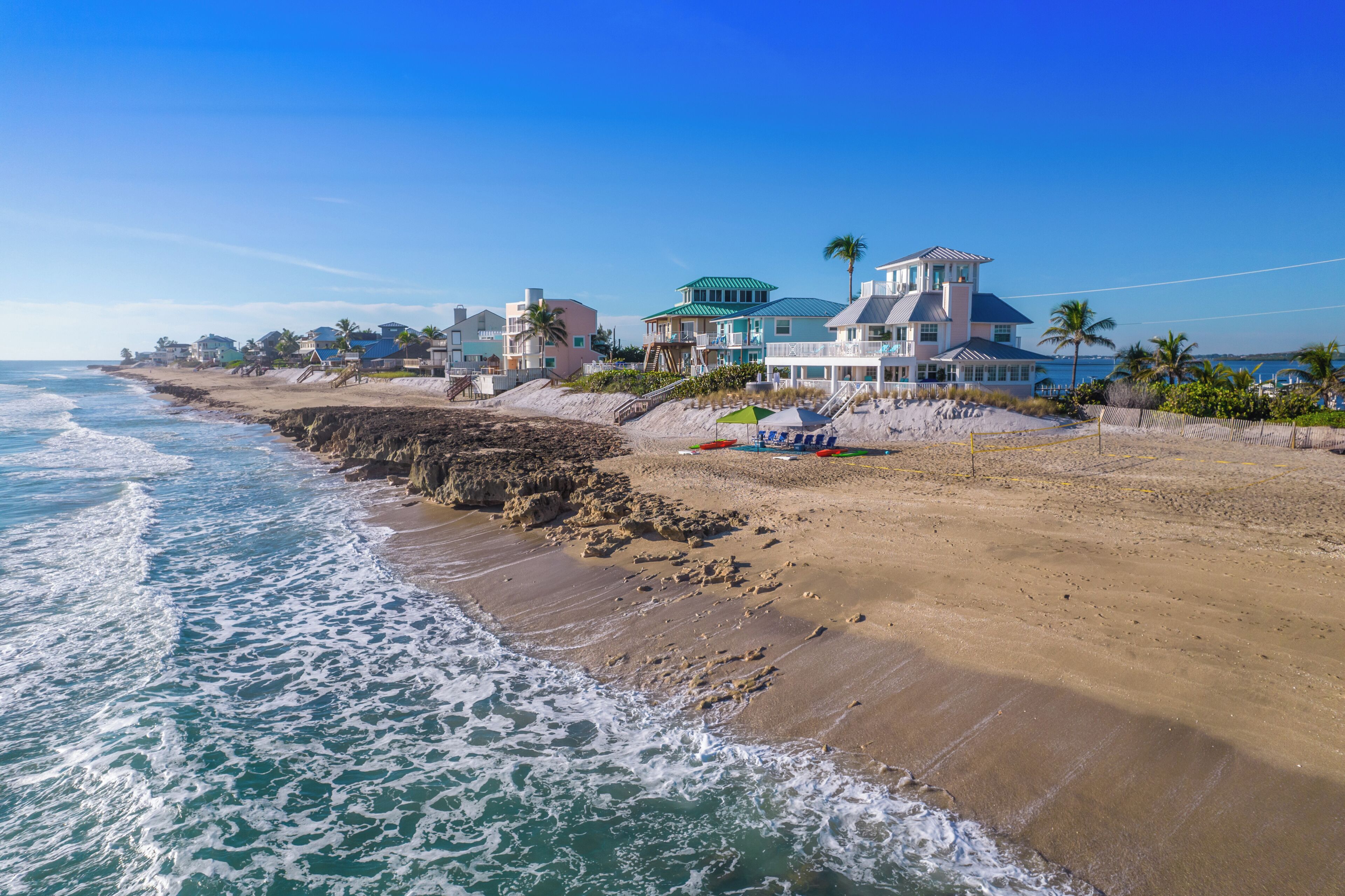 A beachfront property with multiple houses, a sandy beach, and the ocean.