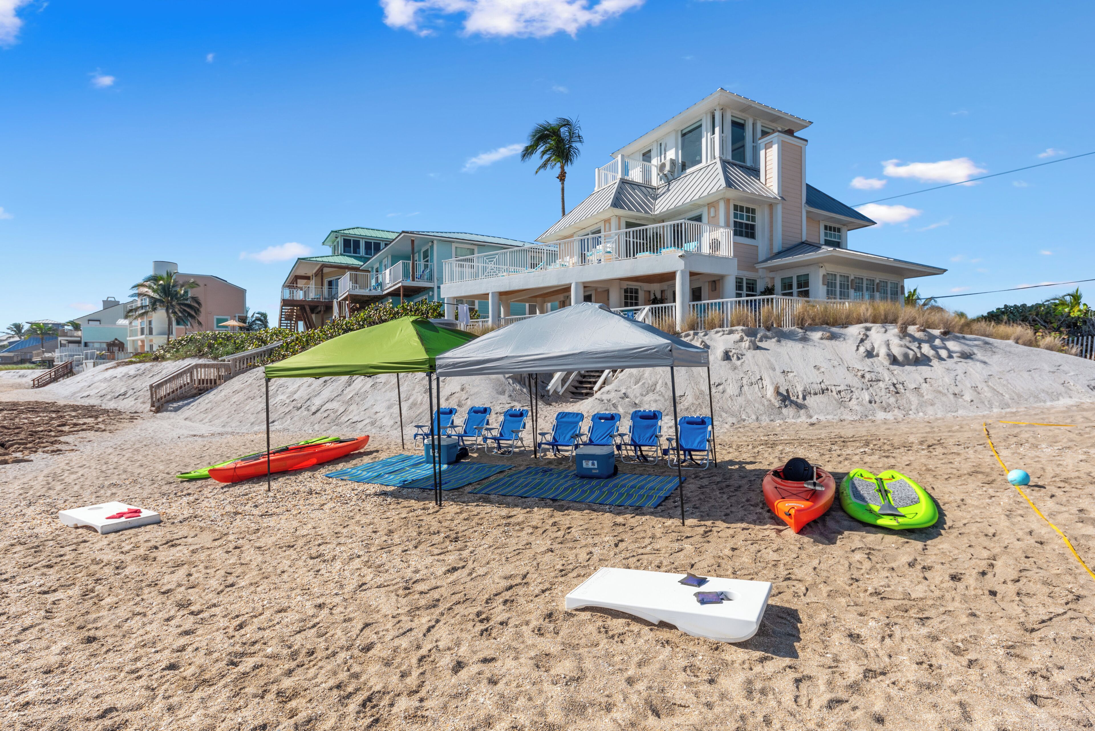 A beach with a tent, kayaks, and lounge chairs.