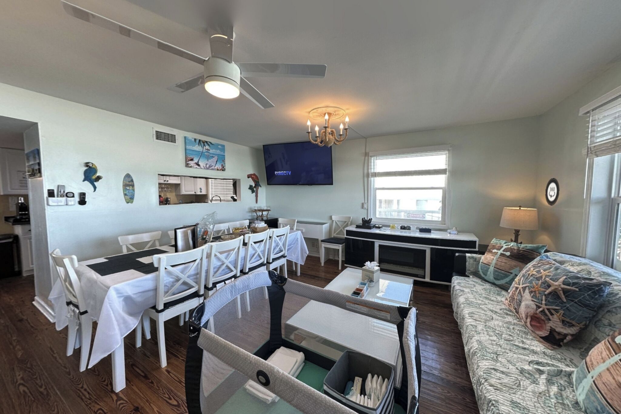 A spacious living area with a dining table, chairs, a sofa, a television, and a kitchen area.