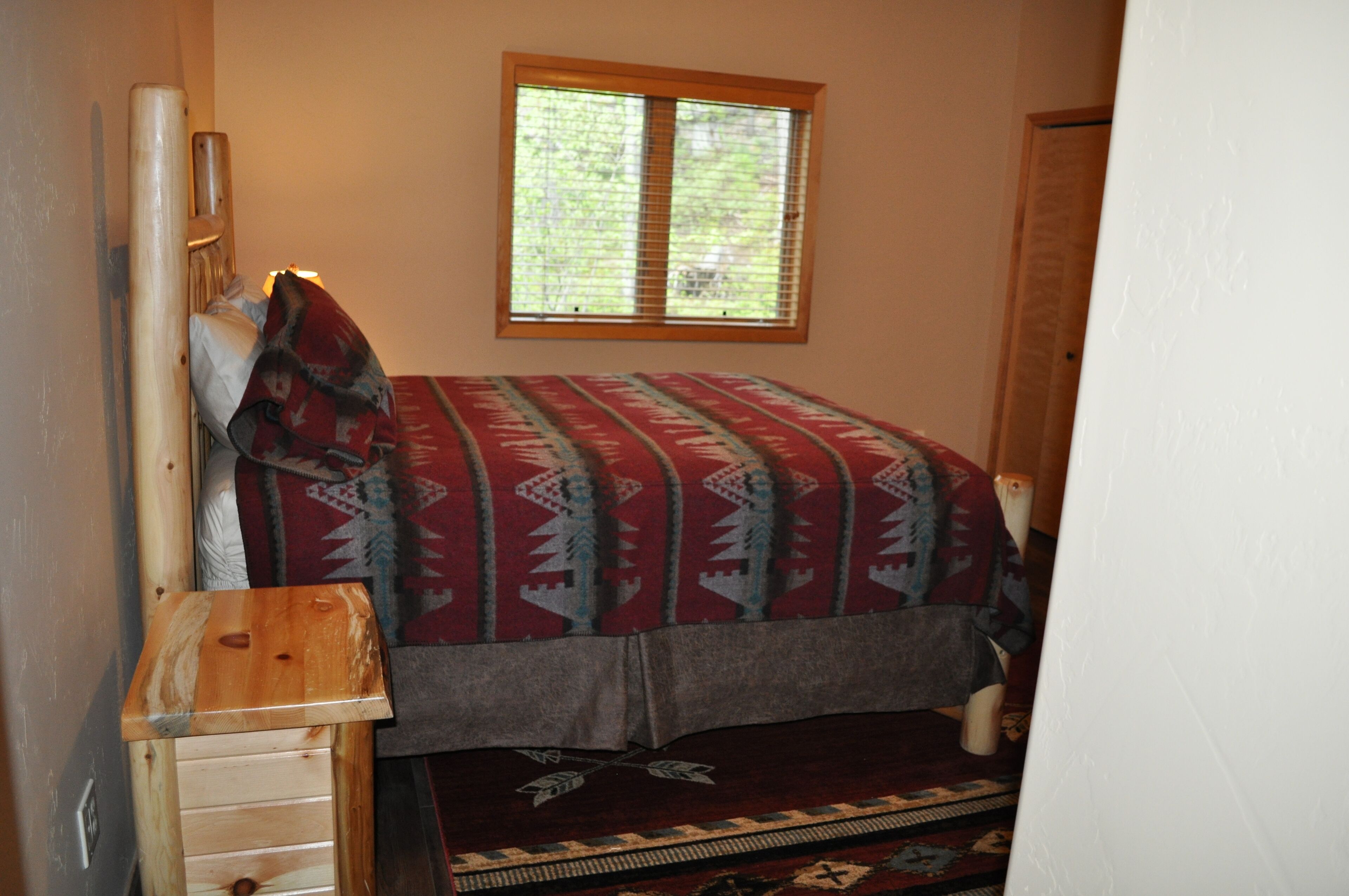 Une petite chambre à coucher avec un lit, une fenêtre et une table de chevet en bois.