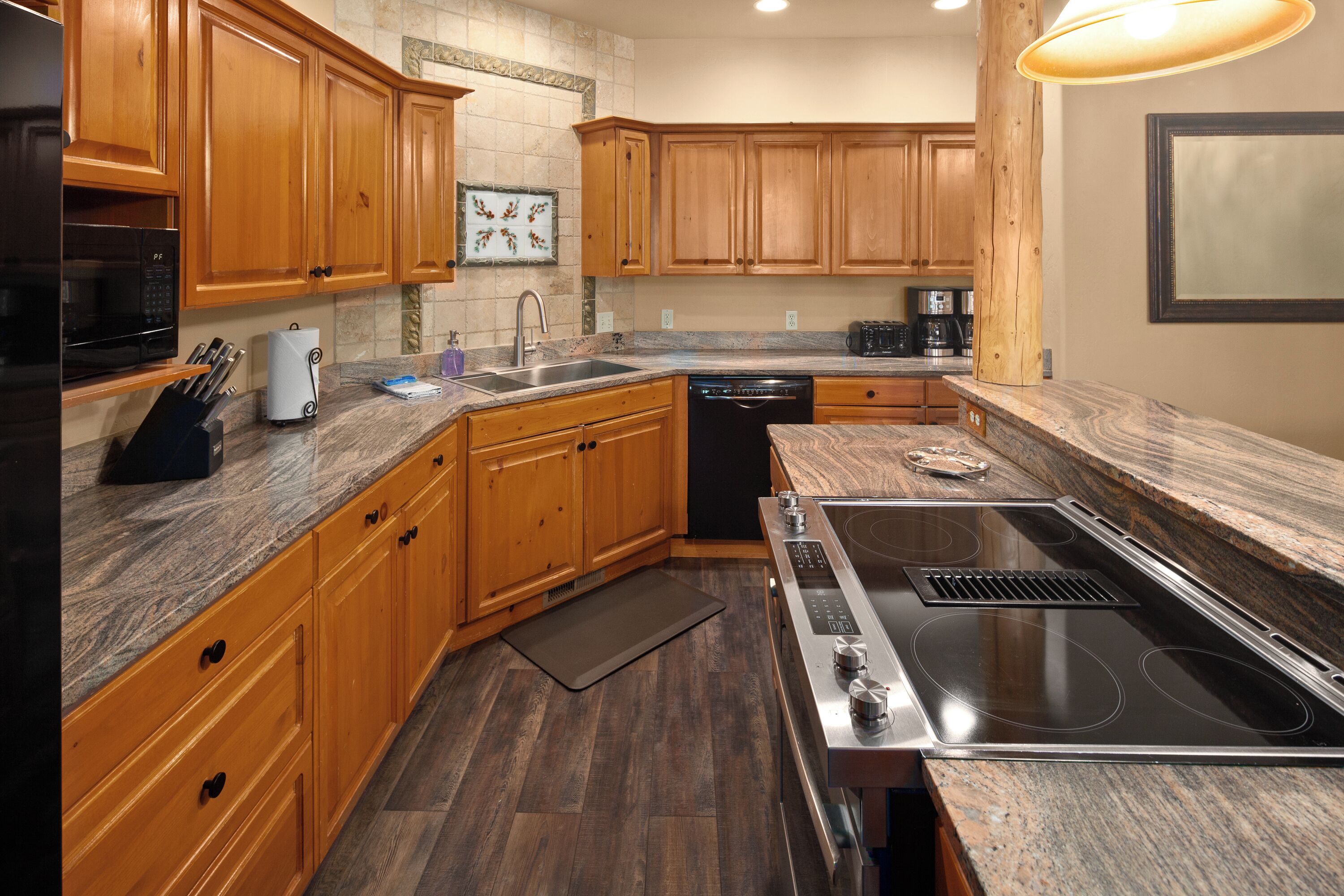 A modern kitchen with wooden cabinets, a stainless steel stove, and a granite countertop.