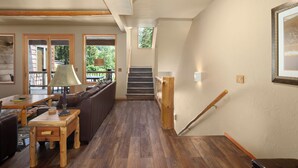 Un vaste espace de vie doté d’un plancher en bois, d’un canapé, d’une table basse et d’un escalier avec une rampe en bois.