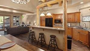 Une cuisine spacieuse avec des meubles de rangement en bois, un grand îlot central doté de tabourets et un luminaire au plafond original.