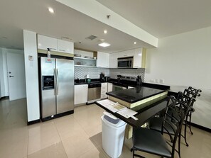 A modern kitchen with stainless steel appliances, a central island, and bar stools.