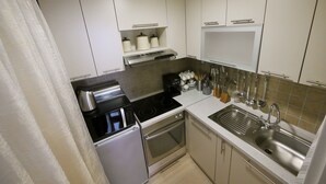 Een functionele keuken met een koelkast, fornuis, oven en spoelbak.