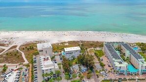 Luchtbeeld van een kusthotel met een strand, parkeerplaats en zwembad.