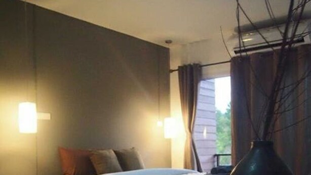 A bedroom with a bed, bedside table, lamp, and a vase. - Fondness Hotel (Takua Pa)