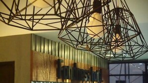 A reception desk with a modern geometric light fixture above it. - Fondness Hotel (Takua Pa)