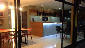 A modern hotel room with a dining area, a kitchen counter, and a large glass window. - Fondness Hotel (Takua Pa)