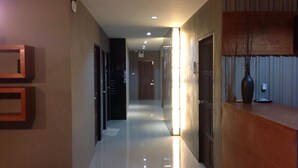 A modern hotel corridor with a polished floor, wooden reception desk, and a minimalist design. - Fondness Hotel (Takua Pa)