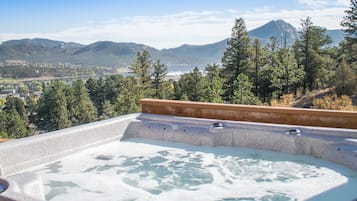 Relax in a hot tub on a terrace with breathtaking views of mountains and a serene natural setting.