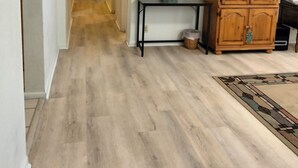 Un pasillo con piso de madera, un armario de madera, una mesita pequeña y una alfombra.