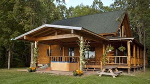 A wooden cabin with a covered porch, outdoor seating, and a hot tub. - Private log cabin with hot tub and mountain views on 14 acres, pet friendly! (N.Ferrisburgh)