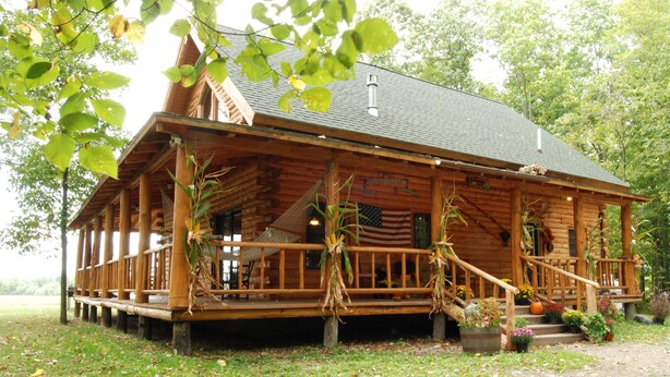 A log cabin with a porch, wooden railings, and a staircase leading to the entrance. - Private log cabin with hot tub and mountain views on 14 acres, pet friendly! (N.Ferrisburgh)