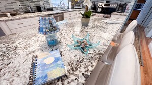 A kitchen with a marble countertop, a toaster, a kettle, and a potted plant. - Quaint Cozy Beach Cape Escape (East Falmouth)